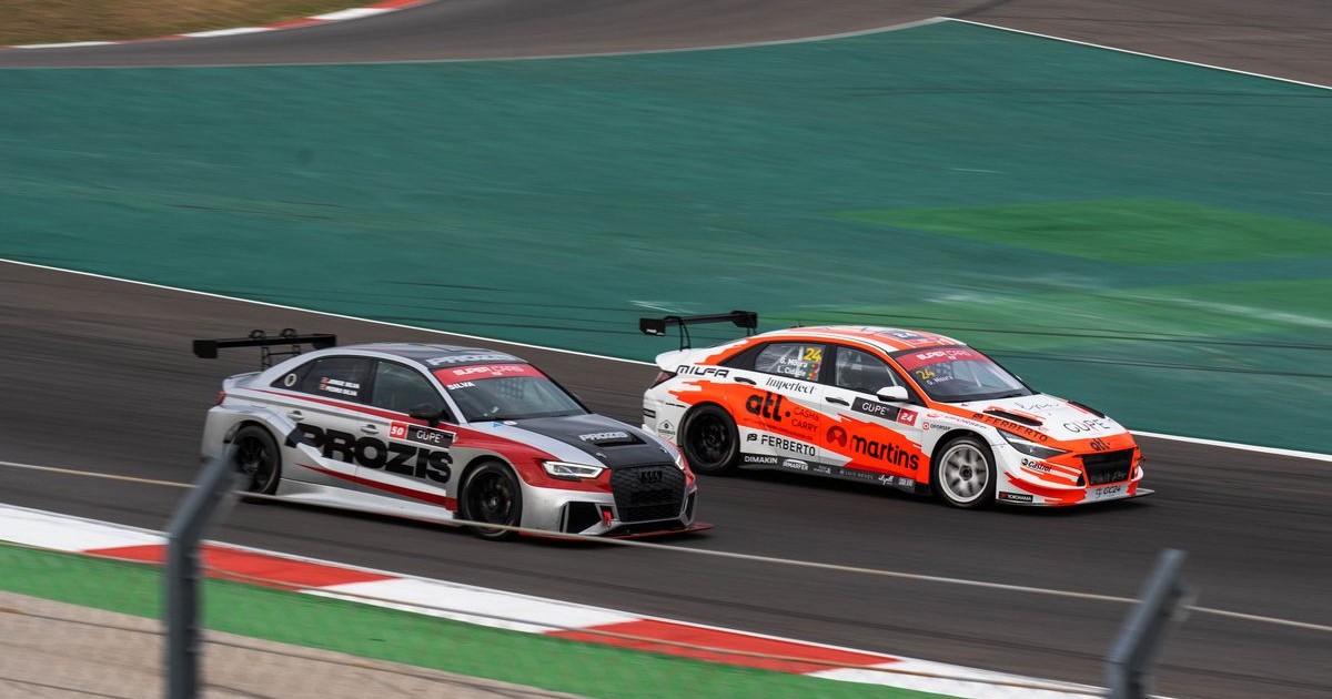 Two race cars competing at speed on a professional paved race circuit, the setting for the track-day coverage question